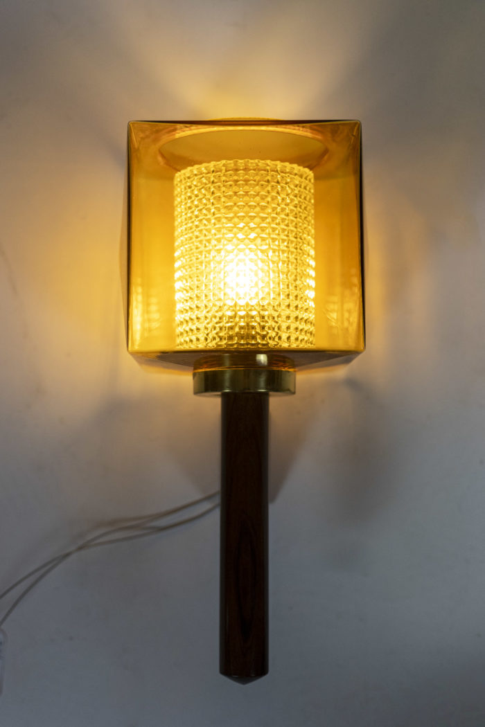 Wall sconce in rosewood and glass, rectangular in shape. Granite glass, translucent and yellow in color - lighted